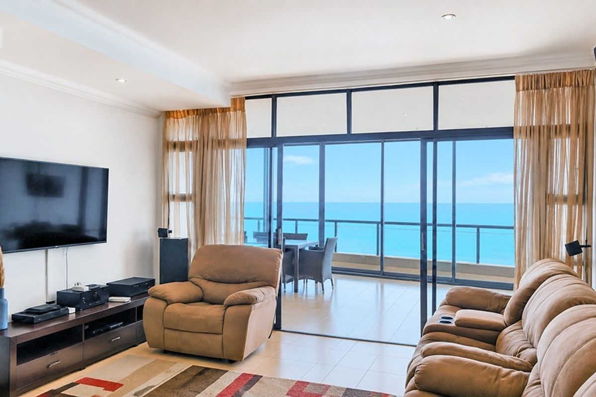 Spacious living room featuring large sliding glass doors that open onto a balcony with expansive ocean views.