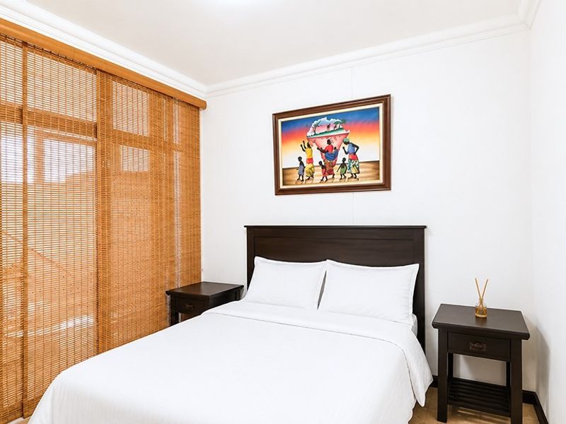 A well-maintained bedroom featuring neutral walls, crown molding, and bamboo-style window blinds, providing a clean and comfortable living space.