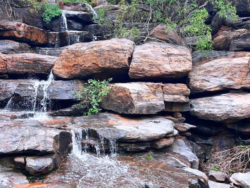A scenic view of a natural rock formation featuring a cascading waterfall on the farm property.