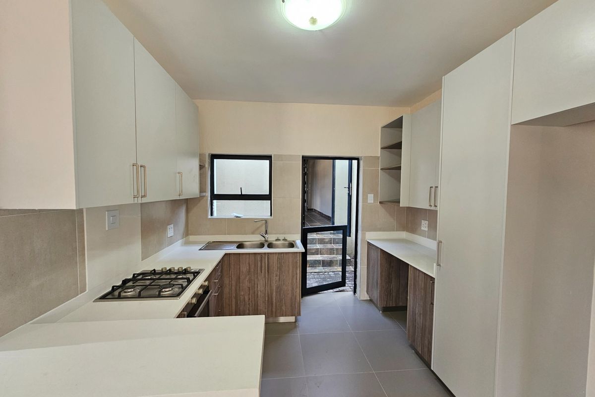 Modern kitchen featuring built-in cabinetry, stone countertops, a gas hob, and tiled flooring, with direct access to an outdoor area.
