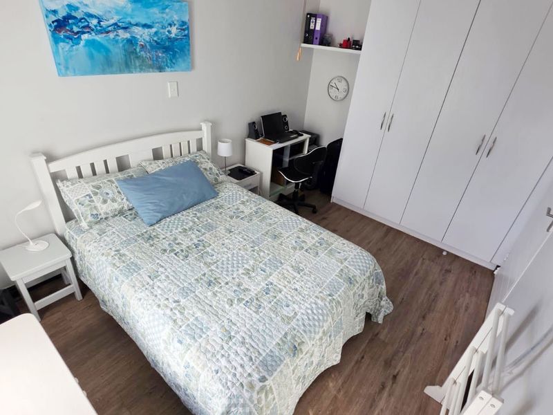 A well-maintained bedroom featuring modern laminate flooring and ample built-in wardrobe storage space.