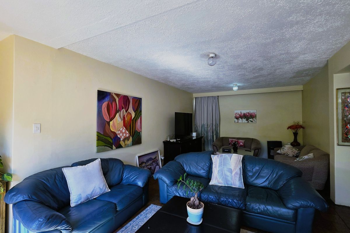 A spacious living room featuring neutral walls, textured ceilings, and ample space for comfortable seating arrangements.