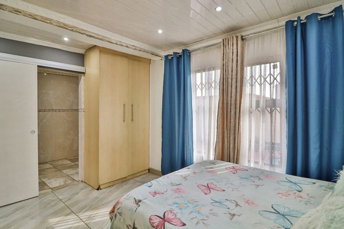 A bedroom featuring tiled flooring, recessed downlighting, a built-in wardrobe, and an en-suite bathroom access via a sliding door.