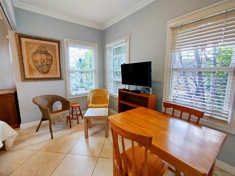 A functional living area featuring tiled flooring, security bars on windows, and venetian blinds, offering a bright and practical space.