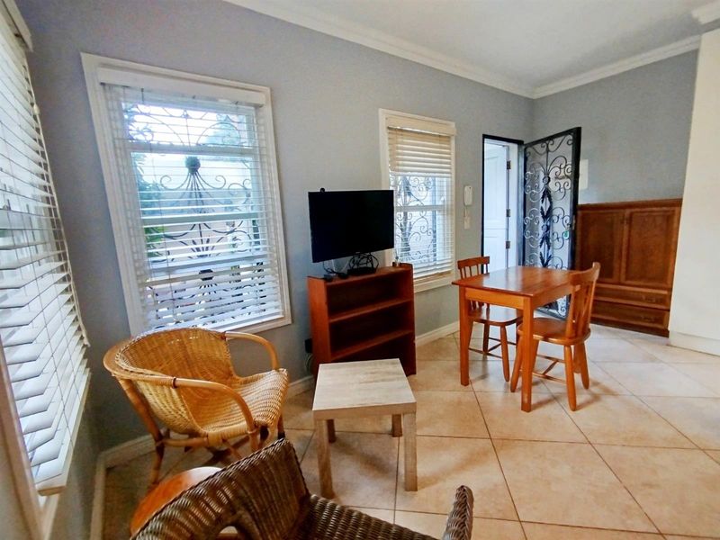 A living area featuring tiled flooring, crown molding, and security-fitted windows and doors, offering a functional space with natural light.