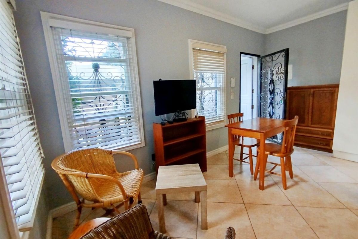 A living area featuring tiled flooring, crown molding, and security-fitted windows and doors, offering a functional space with natural light.