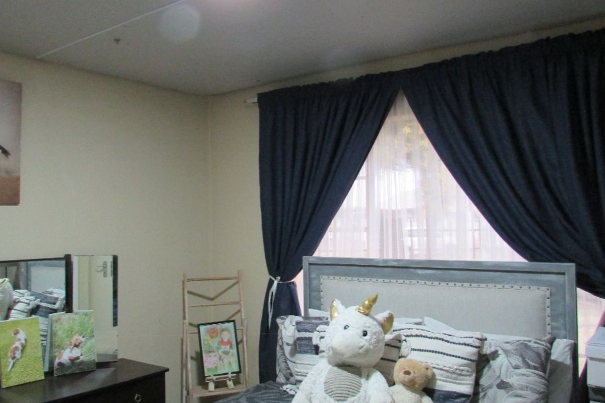 A standard bedroom featuring neutral walls, a ceiling light fixture, and window curtain rails.