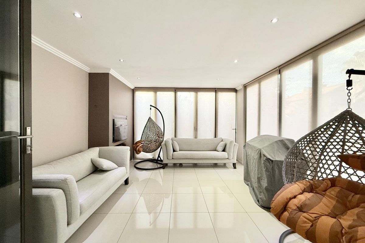 A bright and spacious living room featuring large windows, recessed ceiling lighting, and polished floor tiles, creating a modern and airy atmosphere.