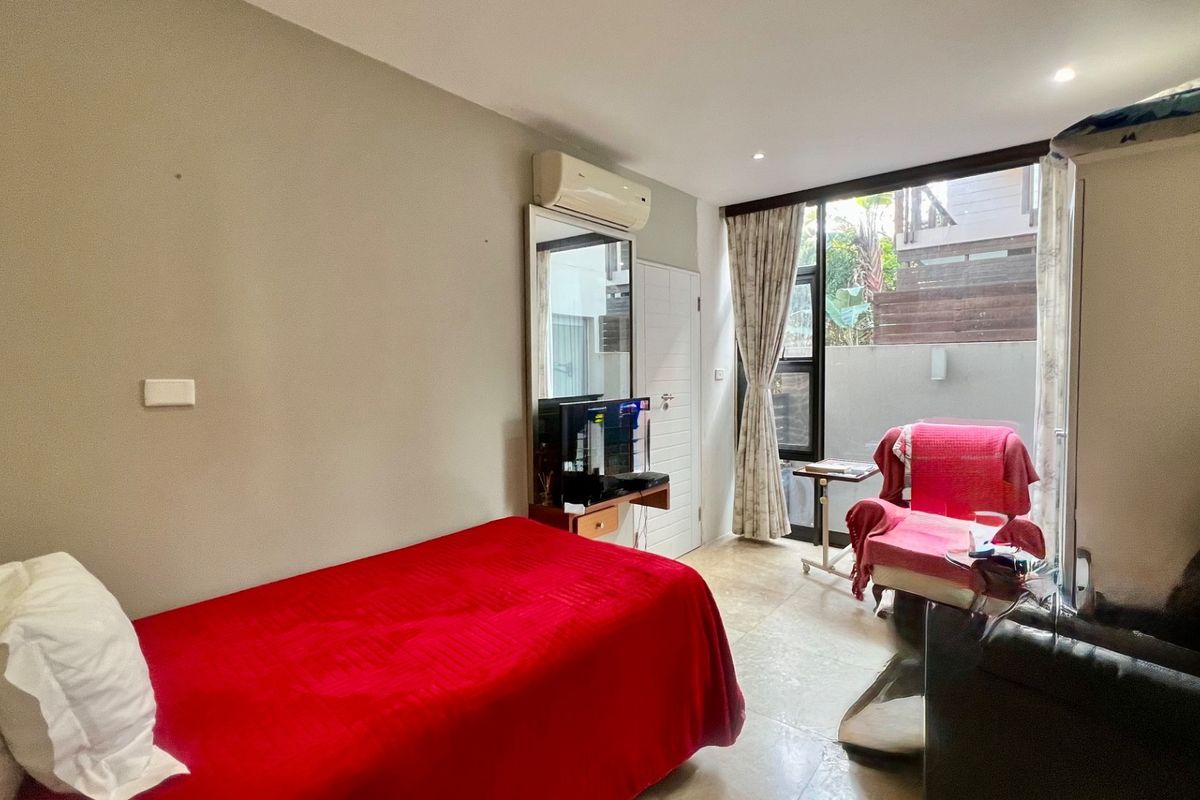 A bedroom featuring tiled flooring, a split-system air conditioner, and a sliding glass door providing access to an outdoor area.