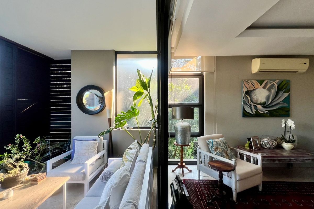 A bright and airy living area featuring large windows, recessed ceiling lighting, and a wall-mounted split-system air conditioner.