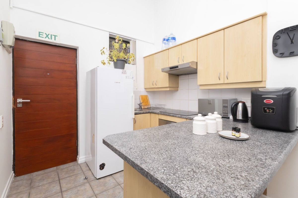 A functional kitchen featuring light wood cabinetry, granite countertops, tiled backsplash, and a tiled floor, providing a practical workspace for daily cooking.