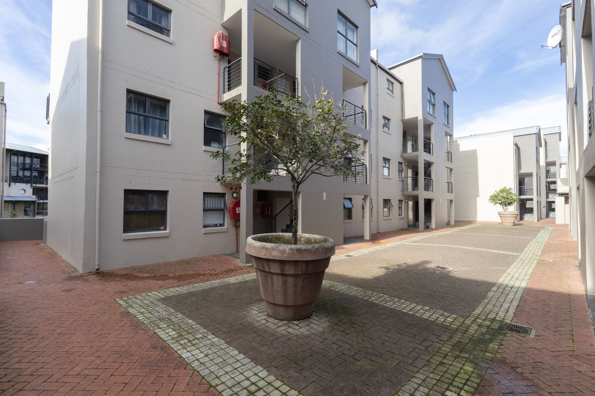 A view of the apartment complex courtyard featuring paved walkways, multi-level balconies, and exterior building infrastructure.