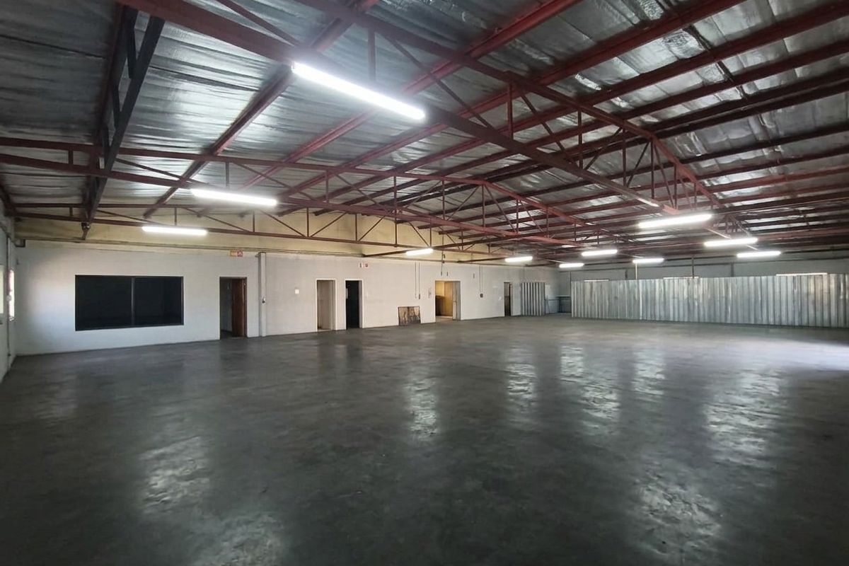 Spacious commercial warehouse or utility space featuring high exposed steel trusses, polished concrete flooring, and functional internal partitioning.