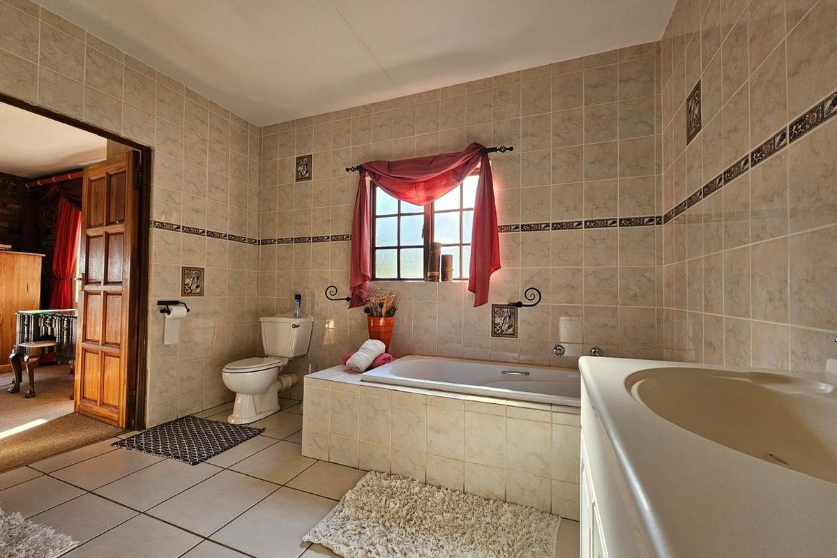 A functional bathroom featuring a built-in bathtub, vanity basin, and toilet, finished with neutral ceramic wall and floor tiles.