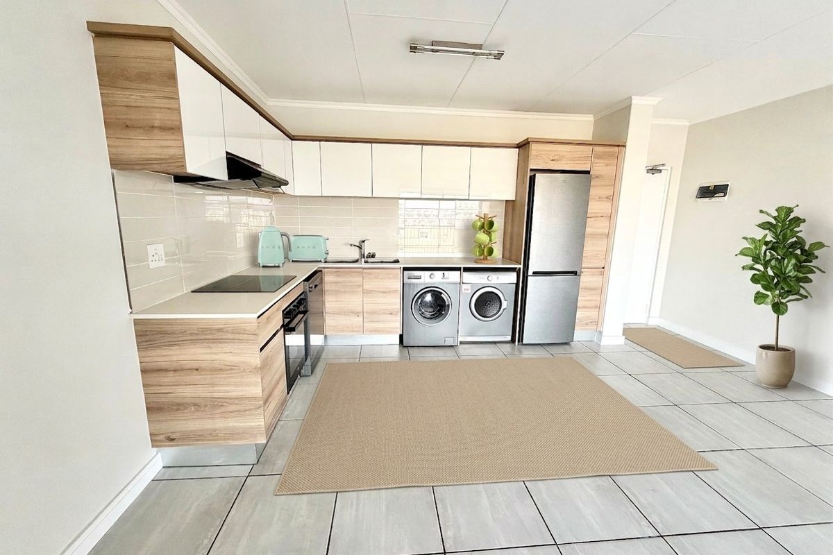 Modern kitchen featuring wood-grain and white cabinetry, integrated appliances, tiled flooring, and a clean, functional layout with ample storage space.