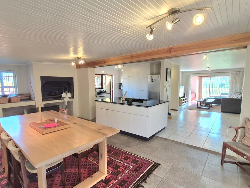 Spacious open-plan living and dining area featuring a central kitchen island, fireplace, and seamless flow to the adjacent lounge space.