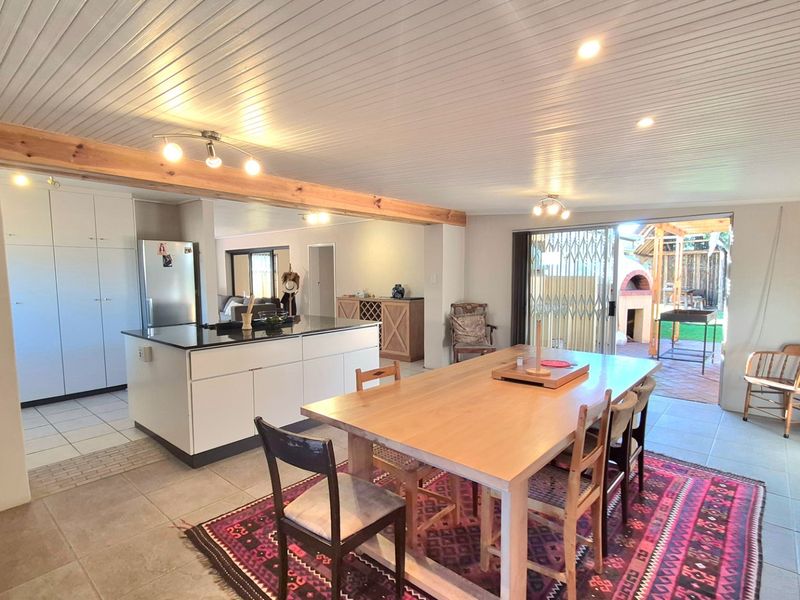Spacious open-plan kitchen and dining area featuring a central island with granite countertops, recessed lighting, and direct access to the outdoor patio.