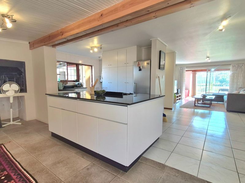 Spacious open-plan living area featuring a modern kitchen island with granite countertops, tiled flooring, and seamless flow to the outdoor patio area.