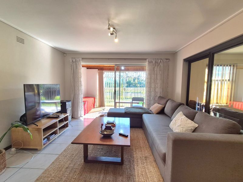 A bright living room featuring tiled flooring and large sliding glass doors that provide access to an outdoor patio area.