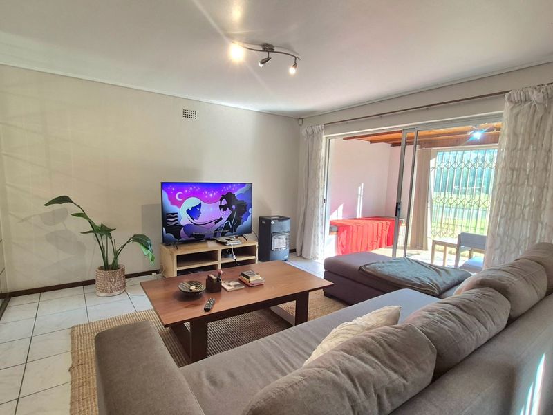 A bright living room featuring tiled flooring and large sliding glass doors that provide direct access to an outdoor patio area.