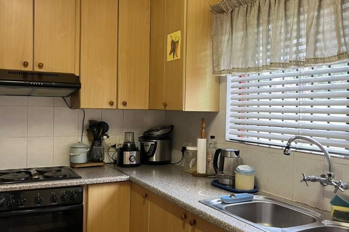 A functional kitchen featuring light wood-tone cabinetry, granite-look laminate countertops, a stainless steel double sink, and built-in cooking appliances.