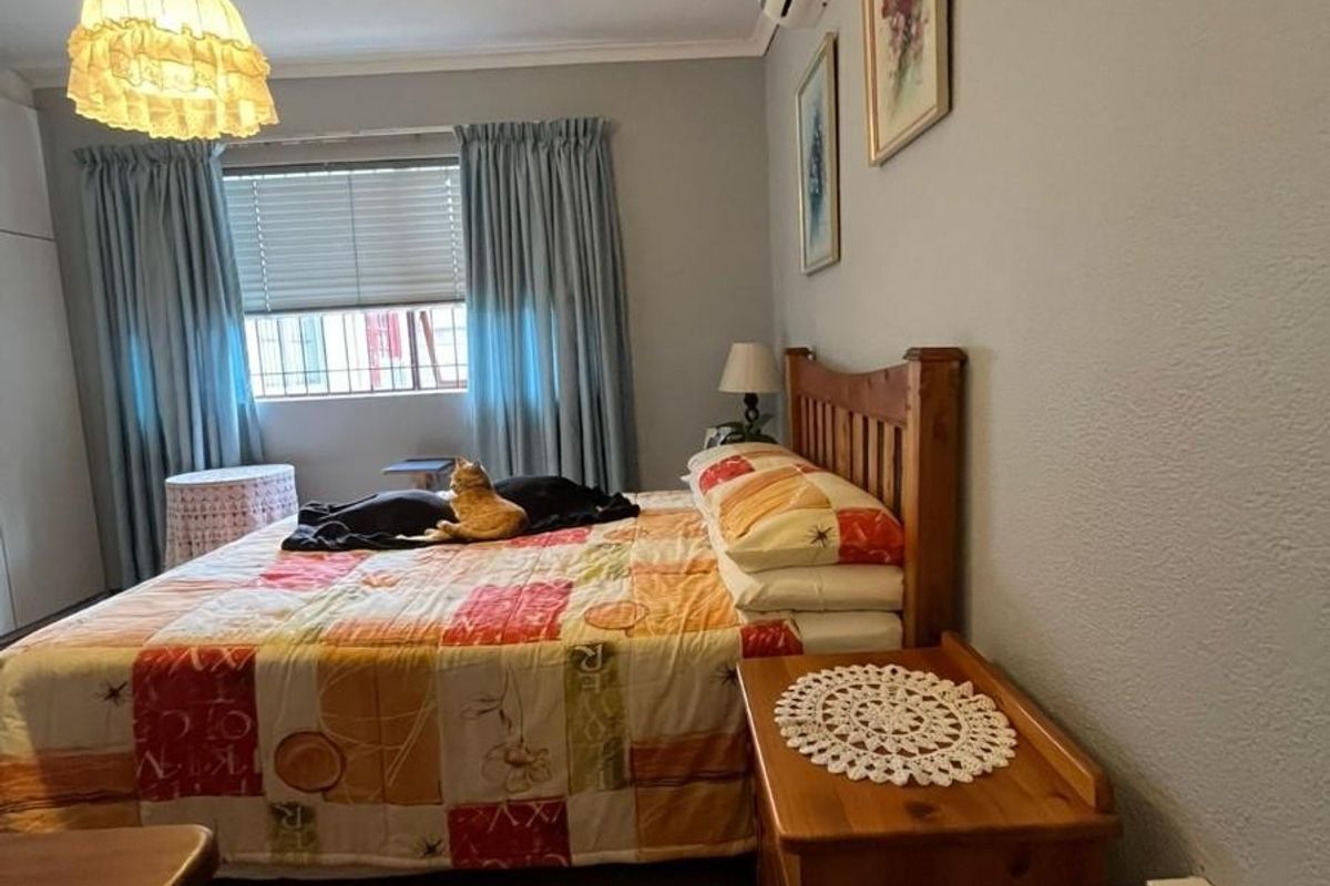 A functional bedroom featuring a split-system air conditioner, built-in wardrobe, and window blinds, offering a comfortable and practical living space.