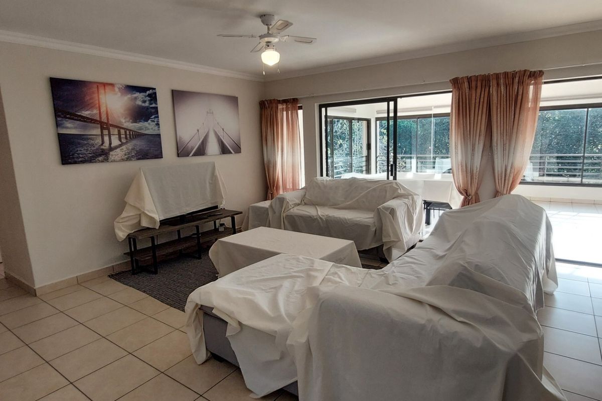 Spacious living room featuring tiled flooring, a ceiling fan, and large sliding glass doors that provide ample natural light and access to the patio.