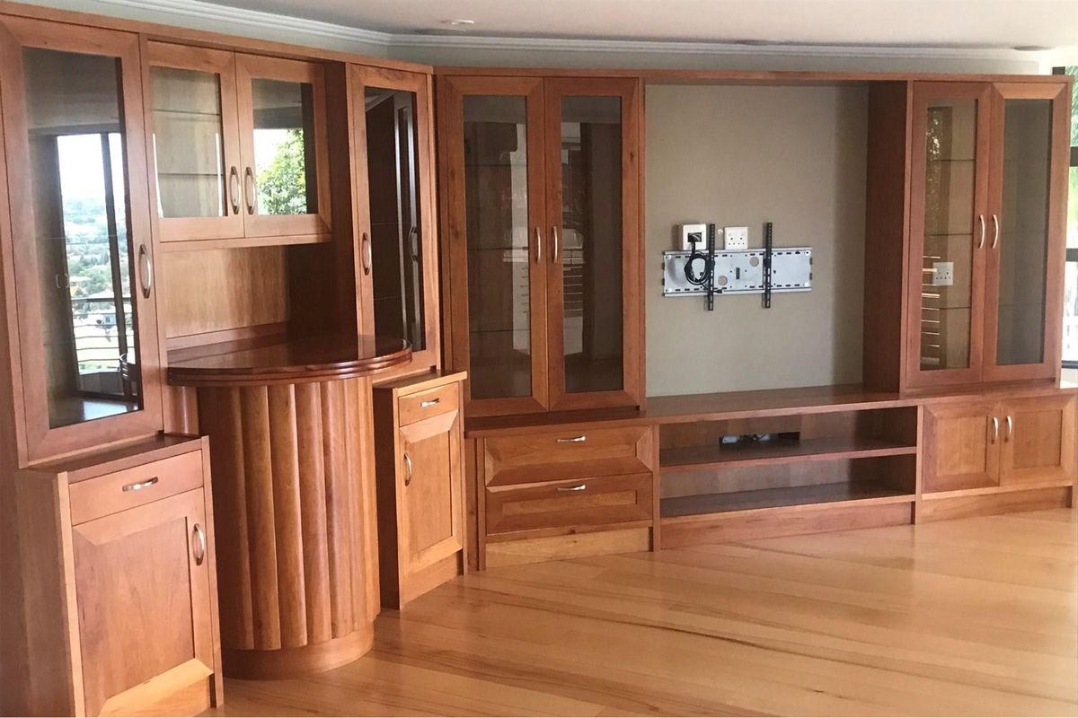 Spacious living area featuring extensive custom built-in wooden cabinetry with glass display sections and polished hardwood flooring.