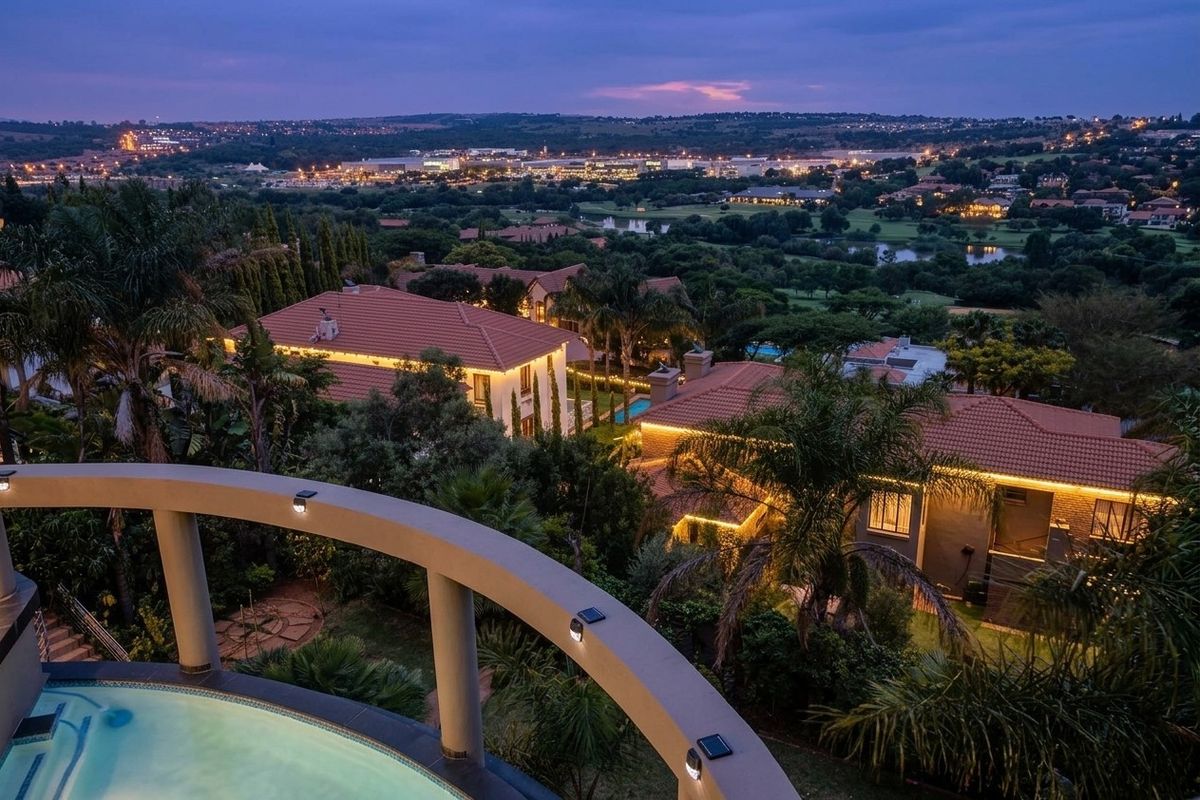 Aerial view at dusk showcasing a residential property with a swimming pool, tiled roofs, and extensive landscape views.
