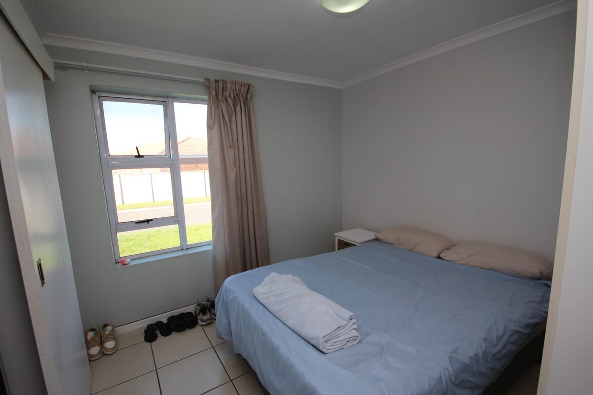 A functional bedroom featuring tiled flooring, a built-in wardrobe, and a window providing natural light.