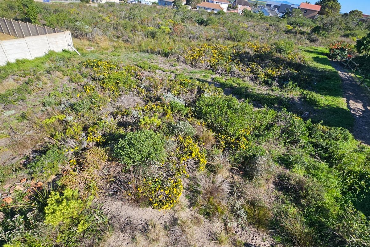 An elevated aerial view of a vacant residential plot featuring natural vegetation and boundary fencing.