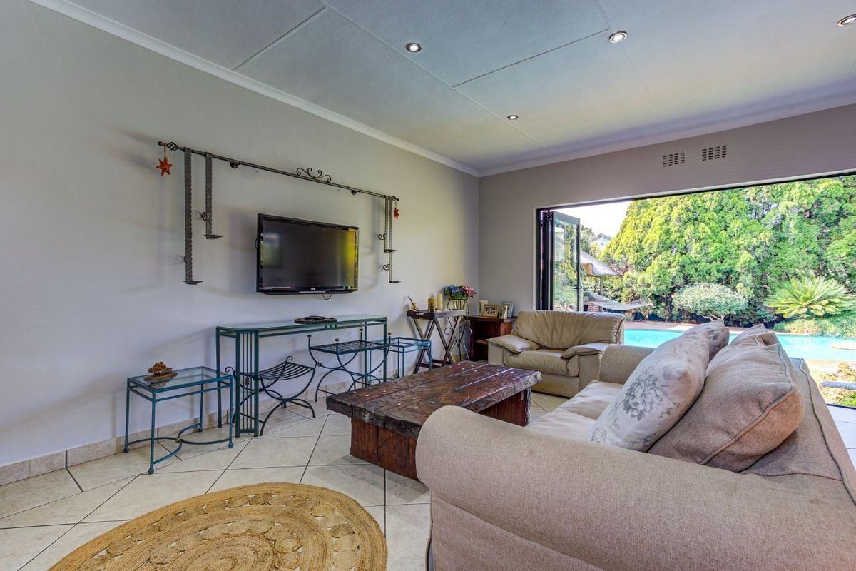 Spacious living room featuring tiled flooring, recessed lighting, and large bi-fold doors that open directly to the outdoor pool area.