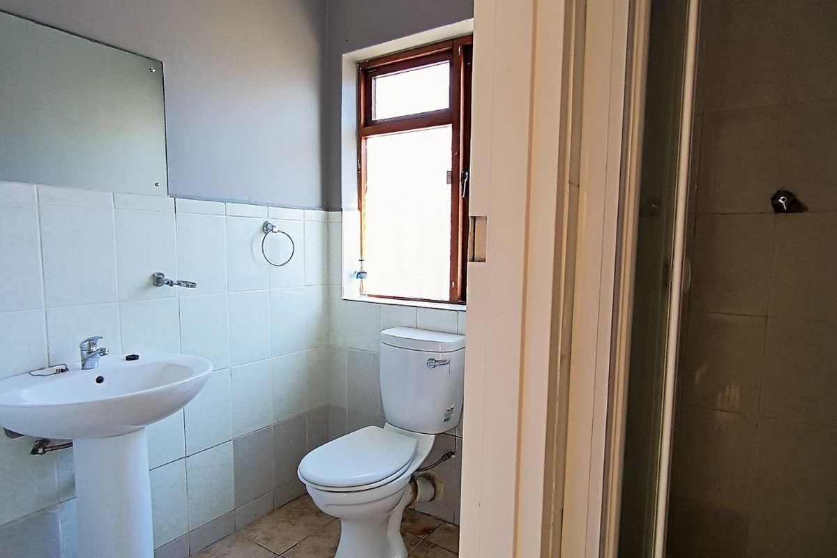 A functional bathroom featuring a pedestal basin, toilet, and a separate shower enclosure with tiled finishes.