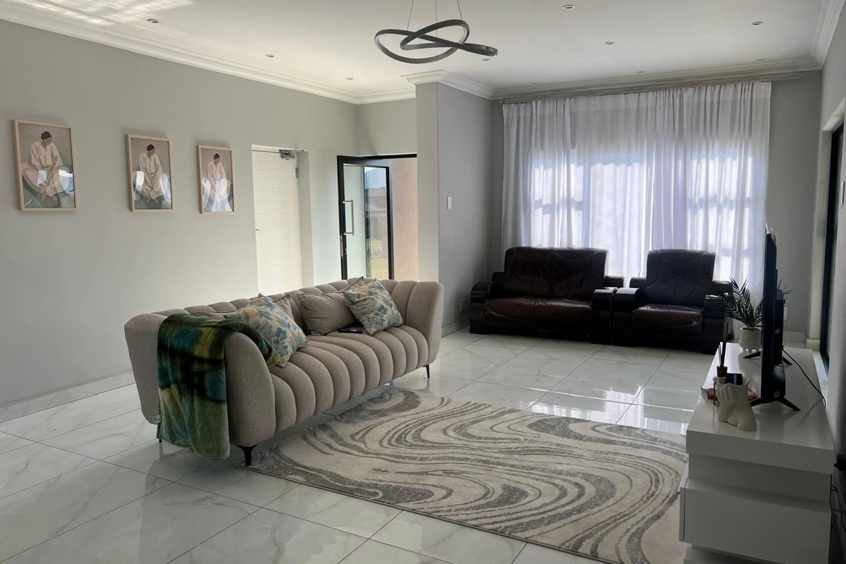 A bright and spacious living room featuring polished porcelain floor tiles, recessed downlighting, and modern coved ceiling cornices.