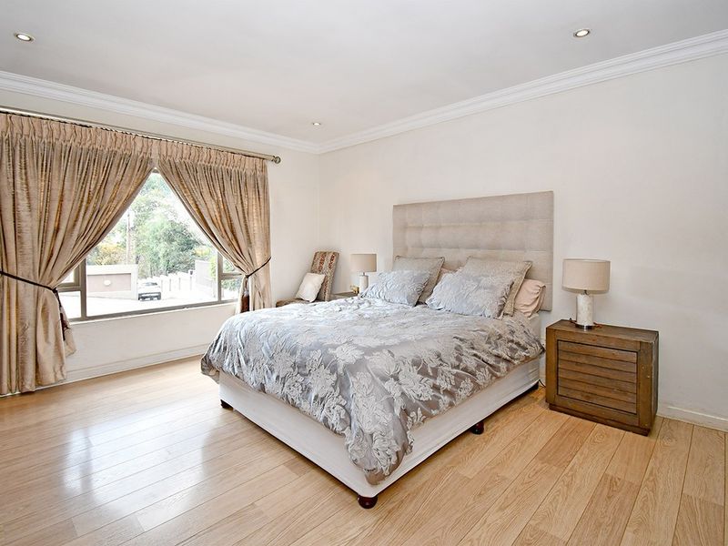 A well-maintained bedroom featuring light-toned laminate flooring, recessed downlighting, crown molding, and a built-in wardrobe.
