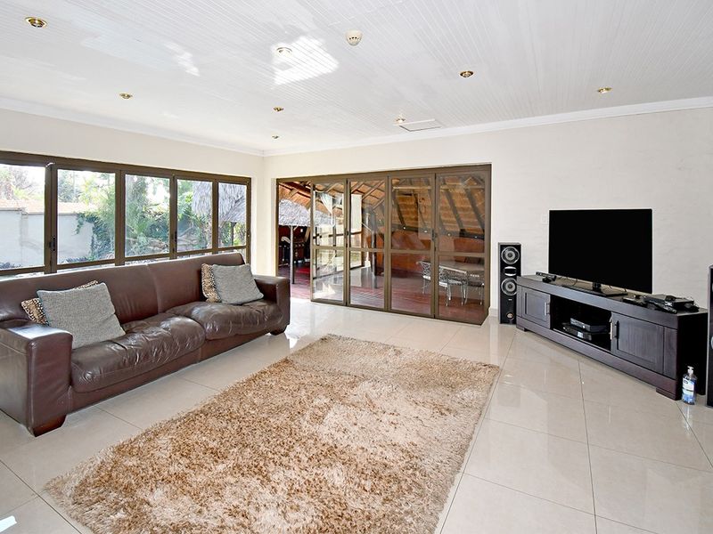Spacious living room featuring large aluminium windows, tiled flooring, and recessed ceiling lighting, with direct access to an outdoor patio area.