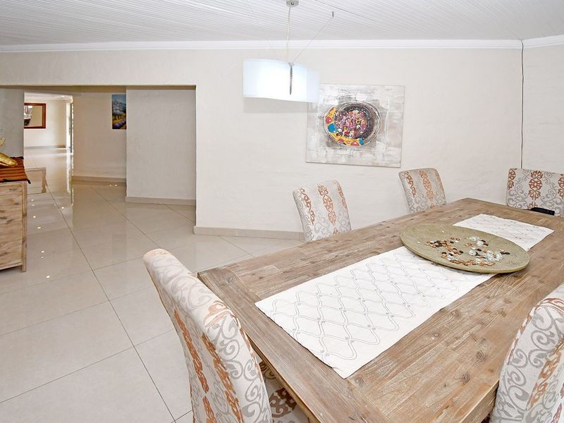 A dining area featuring neutral tiled flooring and a coved ceiling, providing an open-plan flow into the adjacent hallway.