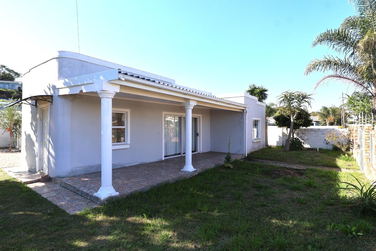 Rear view of the house featuring a covered patio with classical columns, sliding glass doors, and a private garden area.