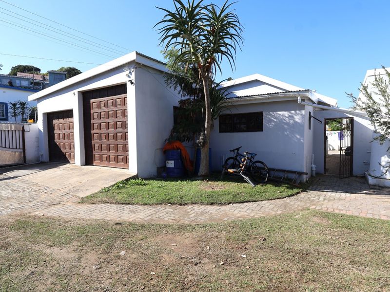 Front exterior view of the property featuring a double garage, paved driveway, and gated side access.