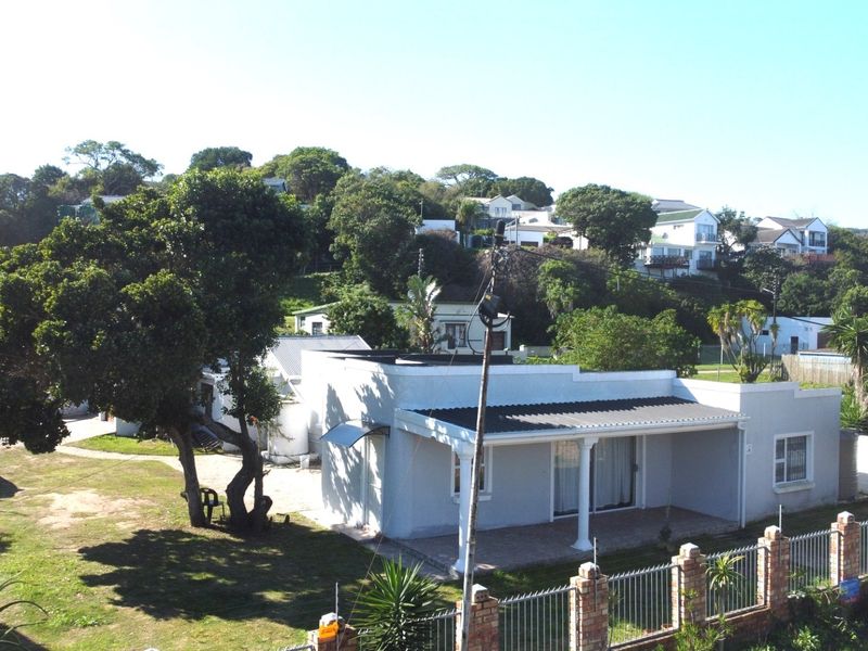A single-story residential property featuring a covered front patio, corrugated metal roof, and a fenced garden area in a suburban setting.