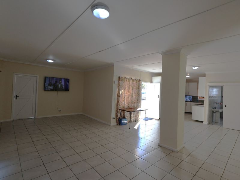 Spacious open-plan living area featuring tiled flooring, a central structural column, and an integrated kitchen space with neutral finishes.