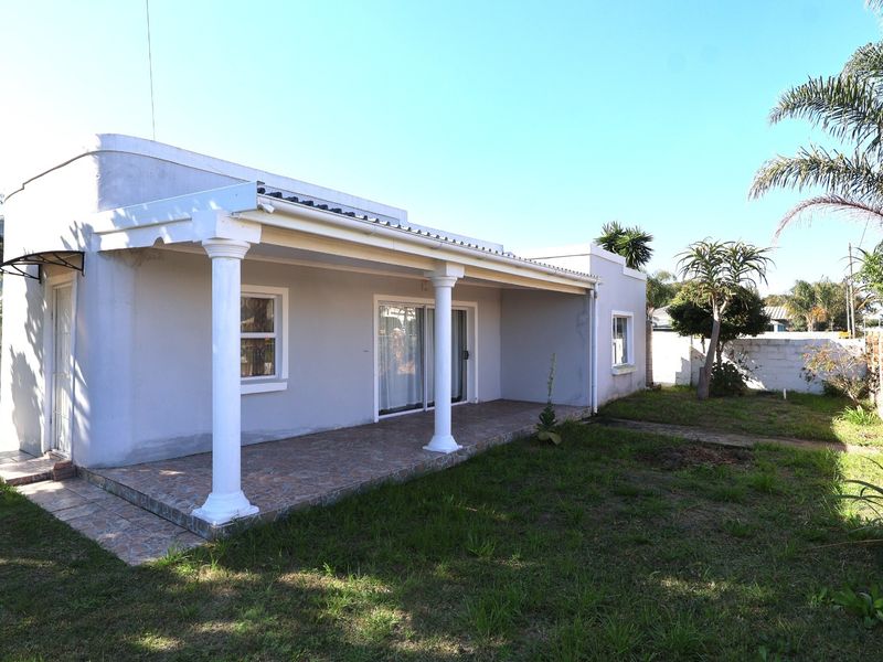 Rear view of the house featuring a covered patio with classical columns, sliding glass doors, and a private garden area.