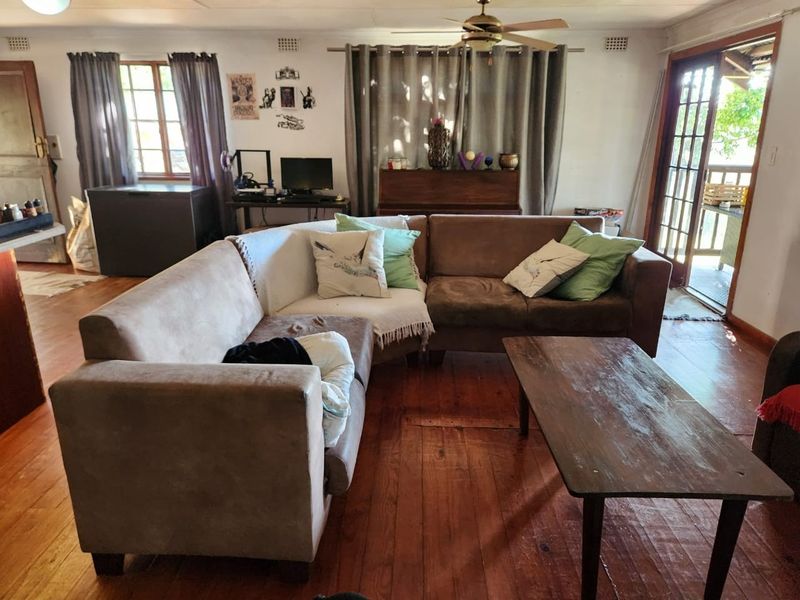 Spacious living room featuring original timber flooring, a ceiling fan, and direct access to an outdoor patio through glass-paneled french doors.