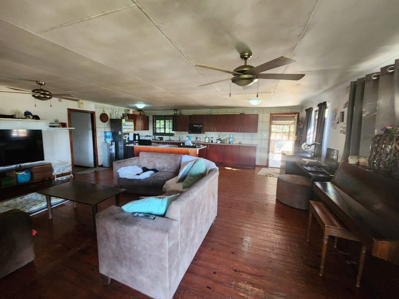 Spacious open-plan living and kitchen area featuring wooden flooring, ceiling fans, and built-in cabinetry, offering a versatile layout for family living.