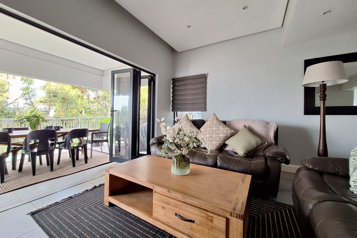 A bright living room featuring large bi-fold doors that open onto an outdoor patio area, creating a seamless indoor-outdoor flow.