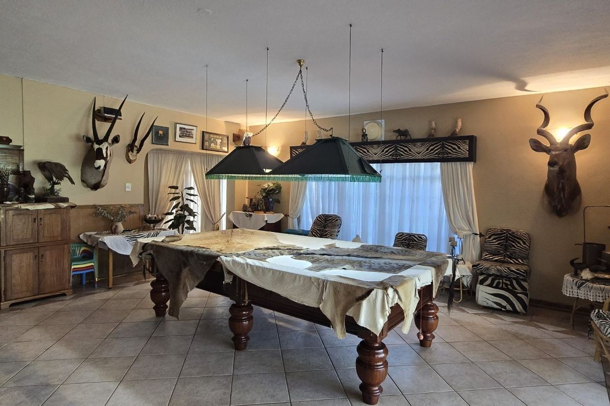 Spacious living area featuring tiled flooring and dual pendant lighting, currently utilized as a recreational space with a central table.