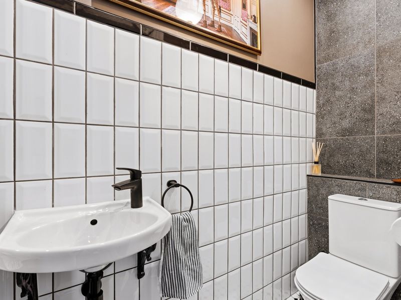 A modern bathroom featuring white subway wall tiles, a stone-effect feature wall, a wall-mounted basin with a black mixer tap, and a standard toilet.