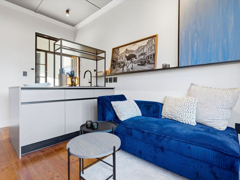 Modern open-plan living area featuring a sleek kitchen island with sink, hardwood flooring, and elegant crown molding in a well-maintained apartment setting.