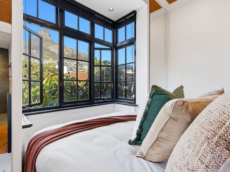 A well-appointed bedroom featuring a prominent bay window with black timber frames, offering scenic mountain views and ample natural light.