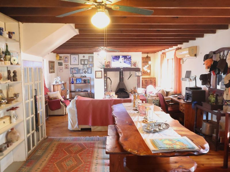 Open plan living and dining area featuring exposed timber ceiling beams, hardwood flooring, and a built-in fireplace.